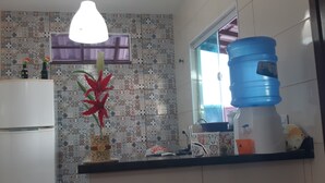 A kitchen with a refrigerator, a water dispenser, and a window with purple curtains. - You in Paradise in Arraial do Cabo, amazing house facing the beach. Do not miss it !! (Arraial do Cabo)