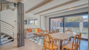 A modern interior with a dining area, a staircase, and a view through large windows. - La Dépendance, Magnifique maison climatisée avec jardin (Bordeaux)