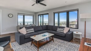 Una sala de estar moderna con un sofá modular, una mesa de centro y ventanas amplias que ofrecen vista a la playa.