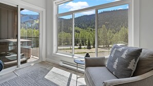 Ein Zimmer mit großem Fenster, einer Schiebetür, einer Couch und einem kleinen Tisch.