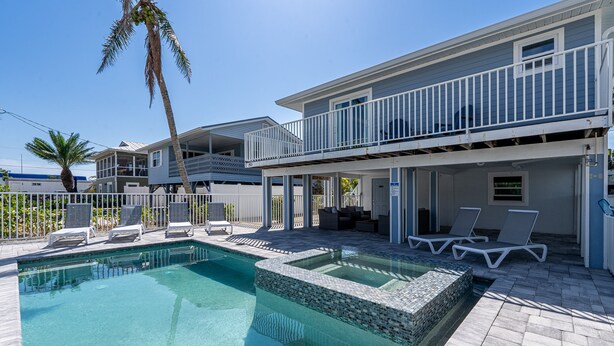 A pool area with lounge chairs and a palm tree. - Large 5BR Home | Pool, Bonus Rooms & Walk to Beach & Dining (Fort Myers Beach)