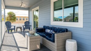 A covered porch with a wicker sofa, two chairs, a small table, and a ceiling fan. - Large 5BR Home | Pool, Bonus Rooms & Walk to Beach & Dining (Fort Myers Beach)