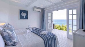 Un dormitorio con cama, un ventanal grande y vista al océano.