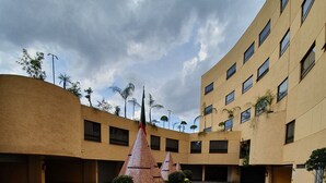 A courtyard with a central brick structure, surrounded by a building with multiple windows and balconies. - Hotel Valle del Sur (Mexico City)