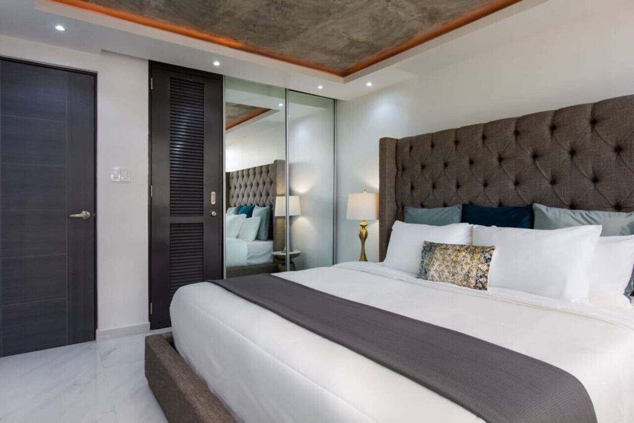 A modern bedroom with a large bed, a dark headboard, and a sliding door closet.