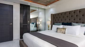 A modern bedroom with a large bed, a dark headboard, and a sliding door closet.