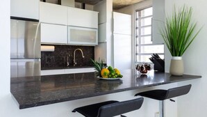 A modern kitchen with white cabinets, a black countertop, and a large window.
