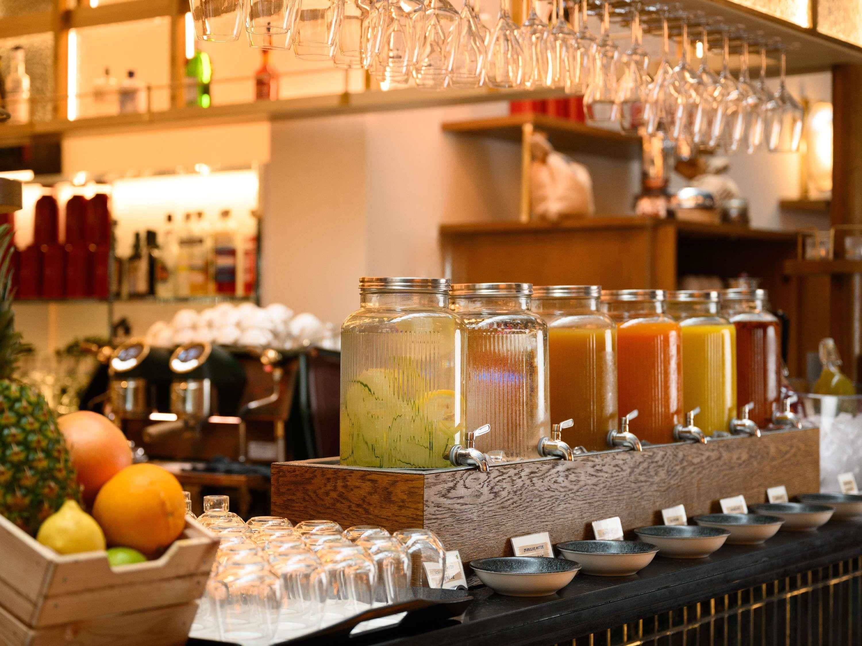 Zona de bar con barra de jugos, vasos y exhibición de frutas.