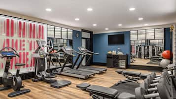 Un gimnasio con cintas de correr, elípticas y bancos para pesas.