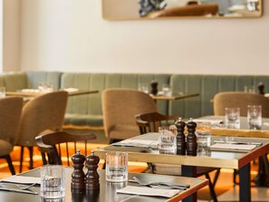 A restaurant with tables set for dining, including glasses, cutlery, and salt and pepper shakers. - Pullman Budapest (Budapest)
