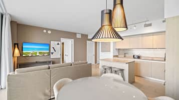 A modern living room with a sofa set, a dining table, and a kitchen area with a central island.