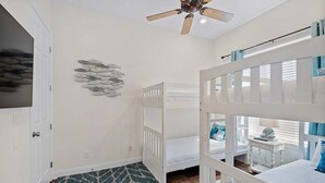 A room with bunk beds, a ceiling fan, a wall-mounted fish decoration, and a patterned rug. - Private Beach | Gulf Views | Comm Pool | Elevator (Destin)