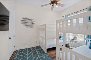 A room with bunk beds, a ceiling fan, a wall-mounted fish decoration, and a patterned rug. - Private Beach | Gulf Views | Comm Pool | Elevator (Destin)