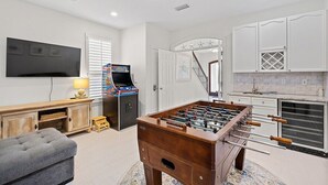 A room with a foosball table, a television, and a gaming console. - Private Beach | Gulf Views | Comm Pool | Elevator (Destin)
