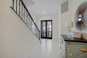 A hallway with a staircase, a door leading outside, a wall-mounted mirror, and a decorative wall piece.