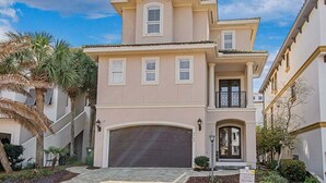 A two-story house with a garage, a balcony, and a well-maintained garden with palm trees. - Private Beach | Gulf Views | Comm Pool | Elevator (Destin)