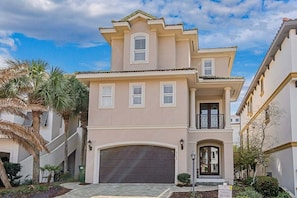 A two-story house with a garage, a balcony, and a well-maintained garden with palm trees. - Private Beach | Gulf Views | Comm Pool | Elevator (Destin)