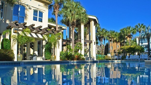 A pool area with a clear reflection of palm trees and a building facade. - Private Beach | Gulf Views | Comm Pool | Elevator (Destin)