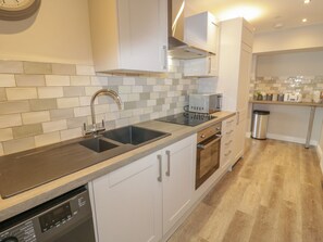 A modern kitchen with a double sink, stainless steel appliances, and a wooden countertop. - The Blue Lion (Corwen)