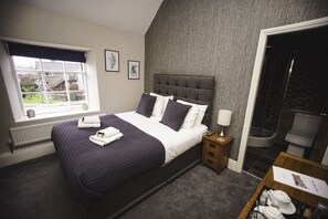 A bedroom with a bed, bedside table, and a view of the outside. - The Blue Lion (Corwen)