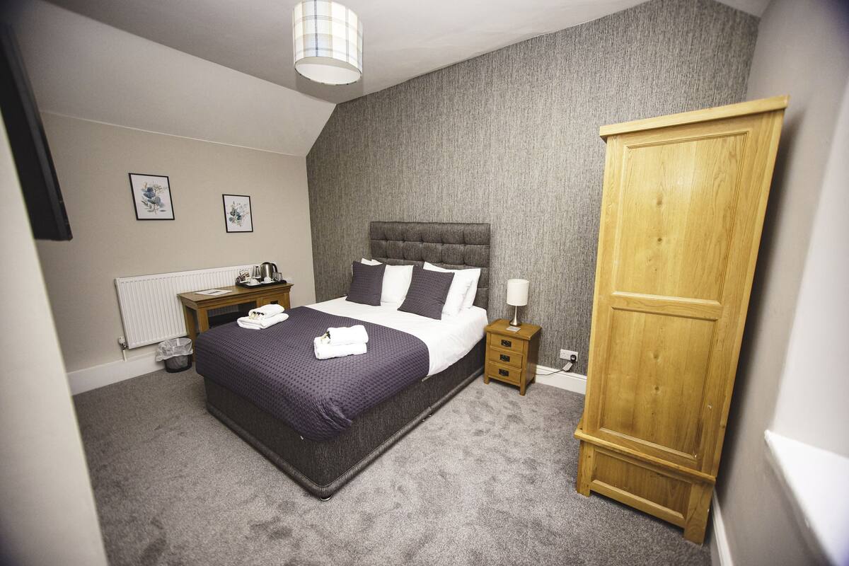 A bedroom with a bed, bedside tables, a wardrobe, and a radiator.