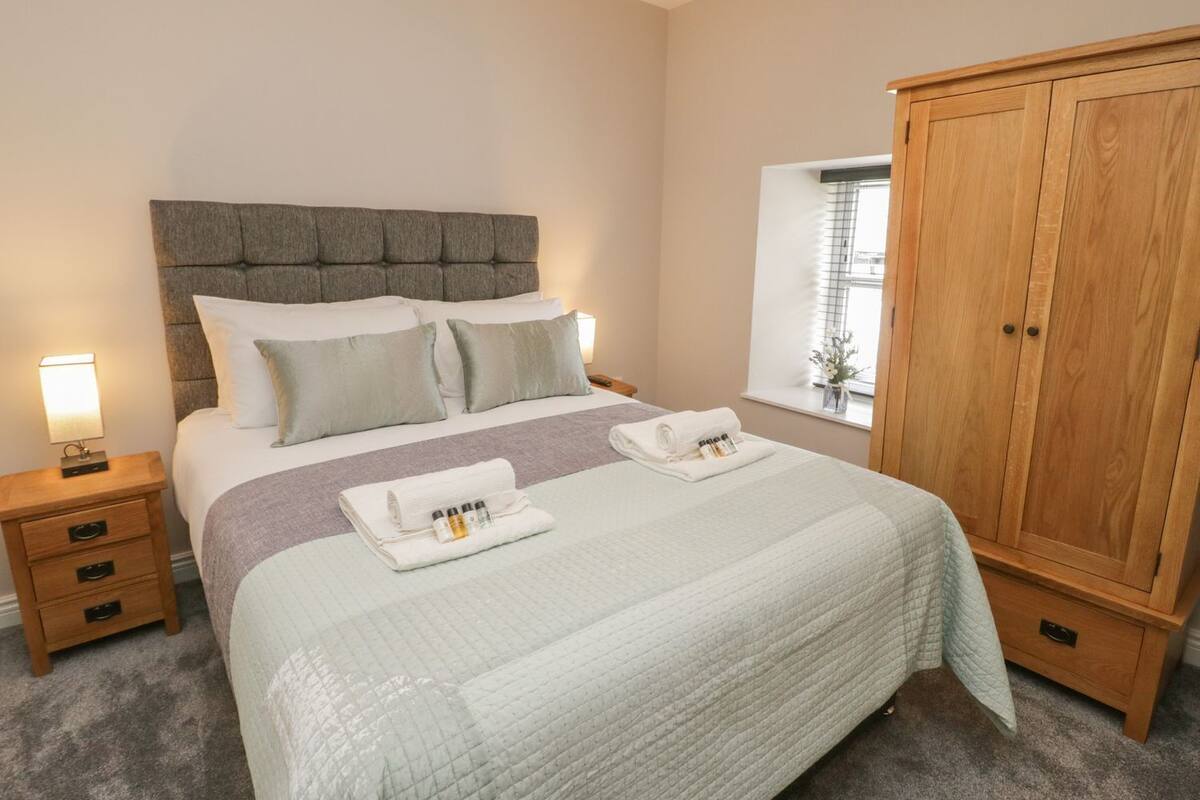 A bedroom with a bed, bedside tables, a wardrobe, and a window.