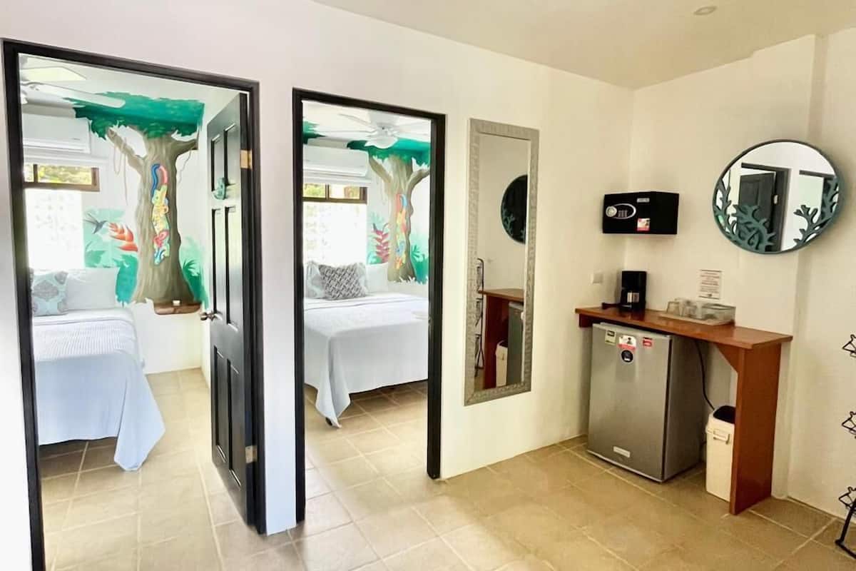 Habitación de hotel con cama, escritorio con refrigerador y espejo en la pared.