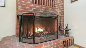 A fireplace with a glass screen, a brick wall, and a small statue of a rabbit on a stand.