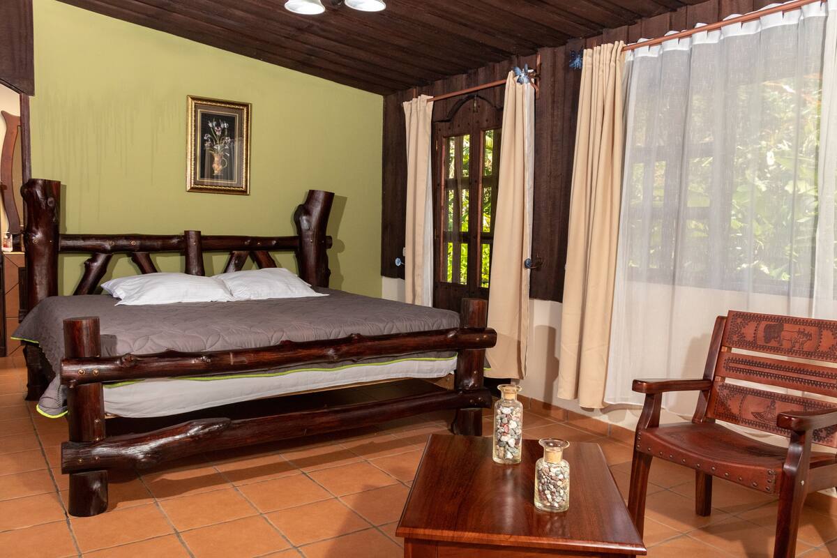 A wooden bed with a headboard, a wooden chair, and a small table with decorative items.