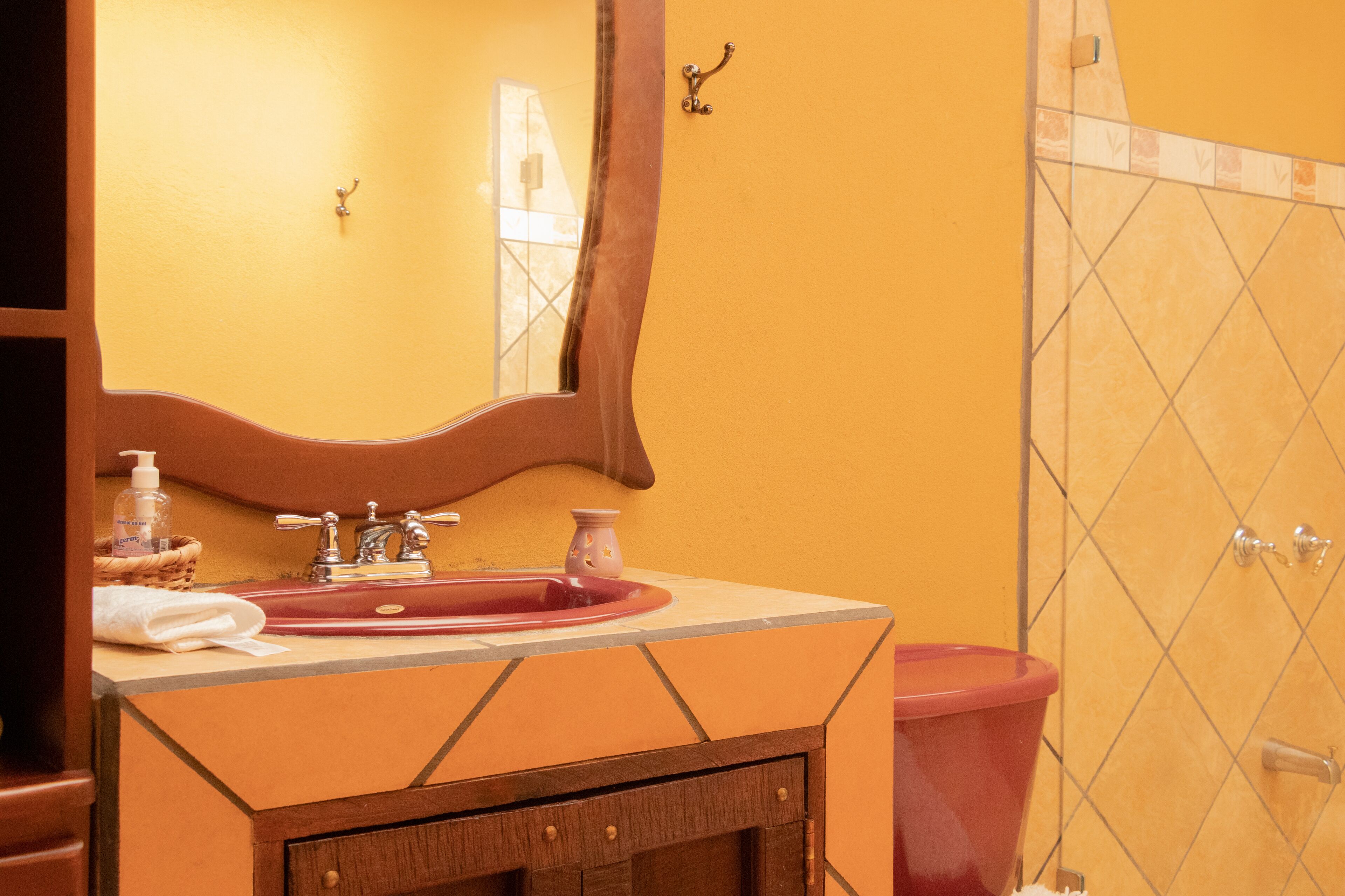 A bathroom with a sink, mirror, and shower area.