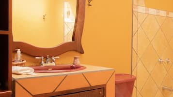 A bathroom with a sink, mirror, and shower area.