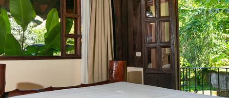 Una habitación con una cama, una puerta de madera y una ventana con cortinas.