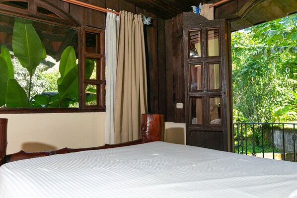 Una habitación con una cama, una puerta de madera y una ventana con cortinas.