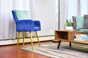 Relax in a stylish living room with a plush armchair, coffee table, and book collection.