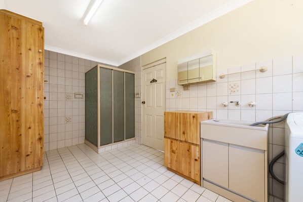 A bathroom with a wooden cabinet, a shower enclosure, a toilet, and a washing machine.
