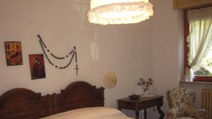 Un dormitorio con una cama grande, cabecera de madera, una mesita de noche, una silla y una lámpara de pared.