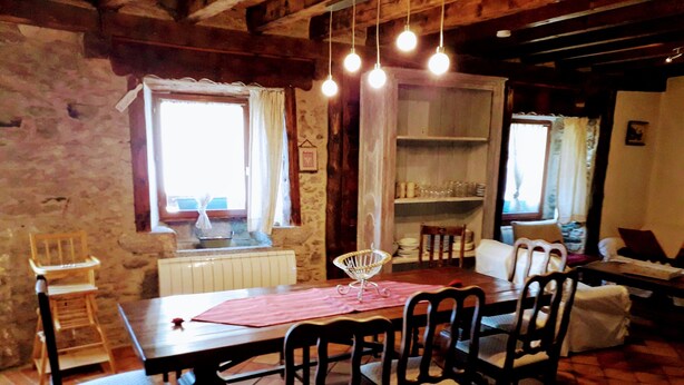 A dining area with a wooden table, chairs, and hanging light bulbs. - Ker Carlines (Targassonne)