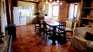 A rustic kitchen with wooden beams, a dining table with chairs, and a white refrigerator. - Ker Carlines (Targassonne)