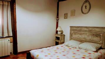A bedroom with a bed, a nightstand, a lamp, and a radiator.