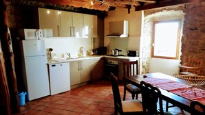 A kitchen with white cabinets, a tiled floor, and a dining table with chairs. - Ker Carlines (Targassonne)