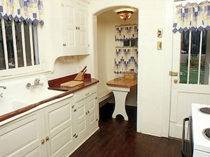 A kitchen with white cabinetry, a wooden countertop, and a built-in stove.