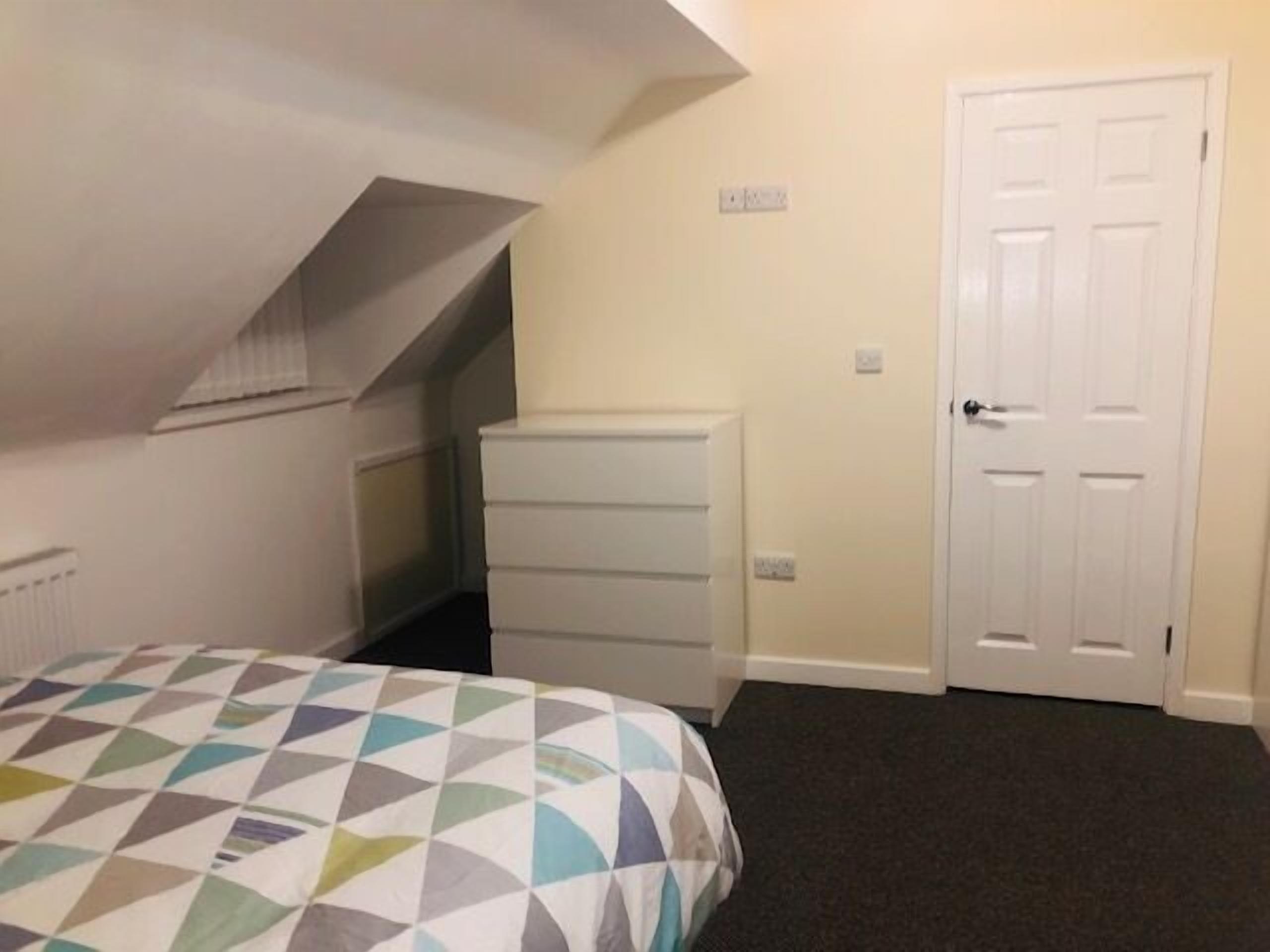 A bedroom with a bed, a dresser, and a door.