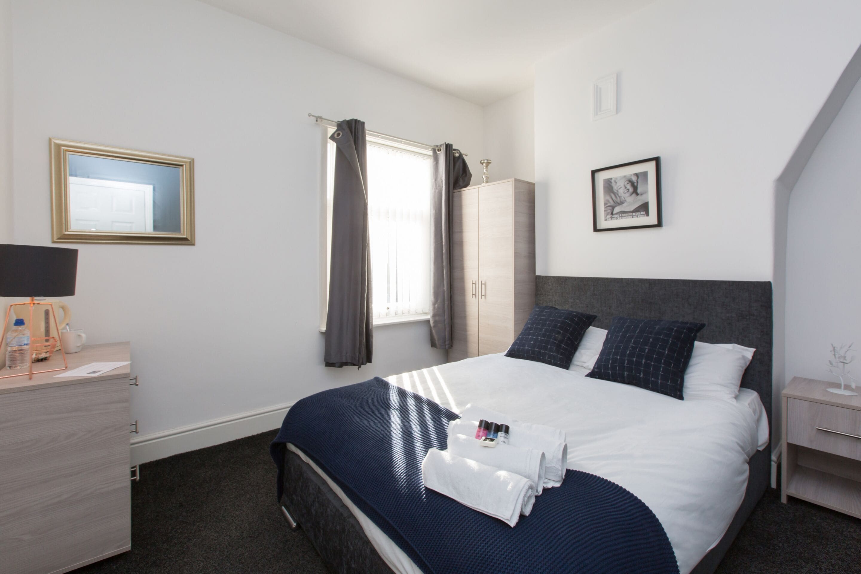 Habitación de hotel ordenada con cama, escritorio, silla y armario.