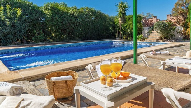 A poolside area with lounge chairs, a table with drinks and snacks, and a clear view of the pool. - Las Adelfas del Gastor by Ruralidays (Cádiz)