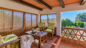 A balcony with wooden furniture, a table with a teapot and cups, and a view of greenery. - Las Adelfas del Gastor by Ruralidays (Cádiz)
