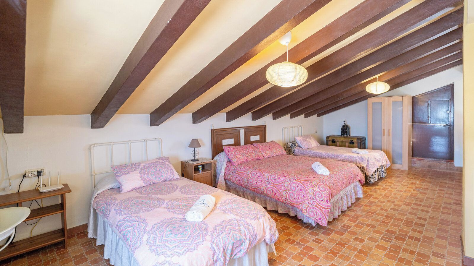Un dormitorio con tres camas, un escritorio y una kitchenette.