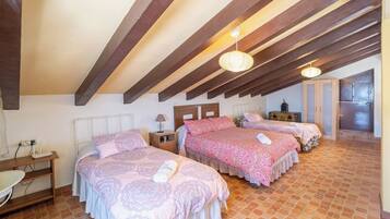 Un dormitorio con tres camas, un escritorio y una kitchenette.