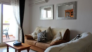 A living room with a sofa, a small table, and two wall-mounted mirrors. - 2 Bed 2 Bath Apt Just Off The Villamartin Plaza, Perfect Location! (Orihuela Costa)
