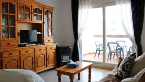 A living room with a wooden cabinet, a television, a small table, and a sofa. - 2 Bed 2 Bath Apt Just Off The Villamartin Plaza, Perfect Location! (Orihuela Costa)