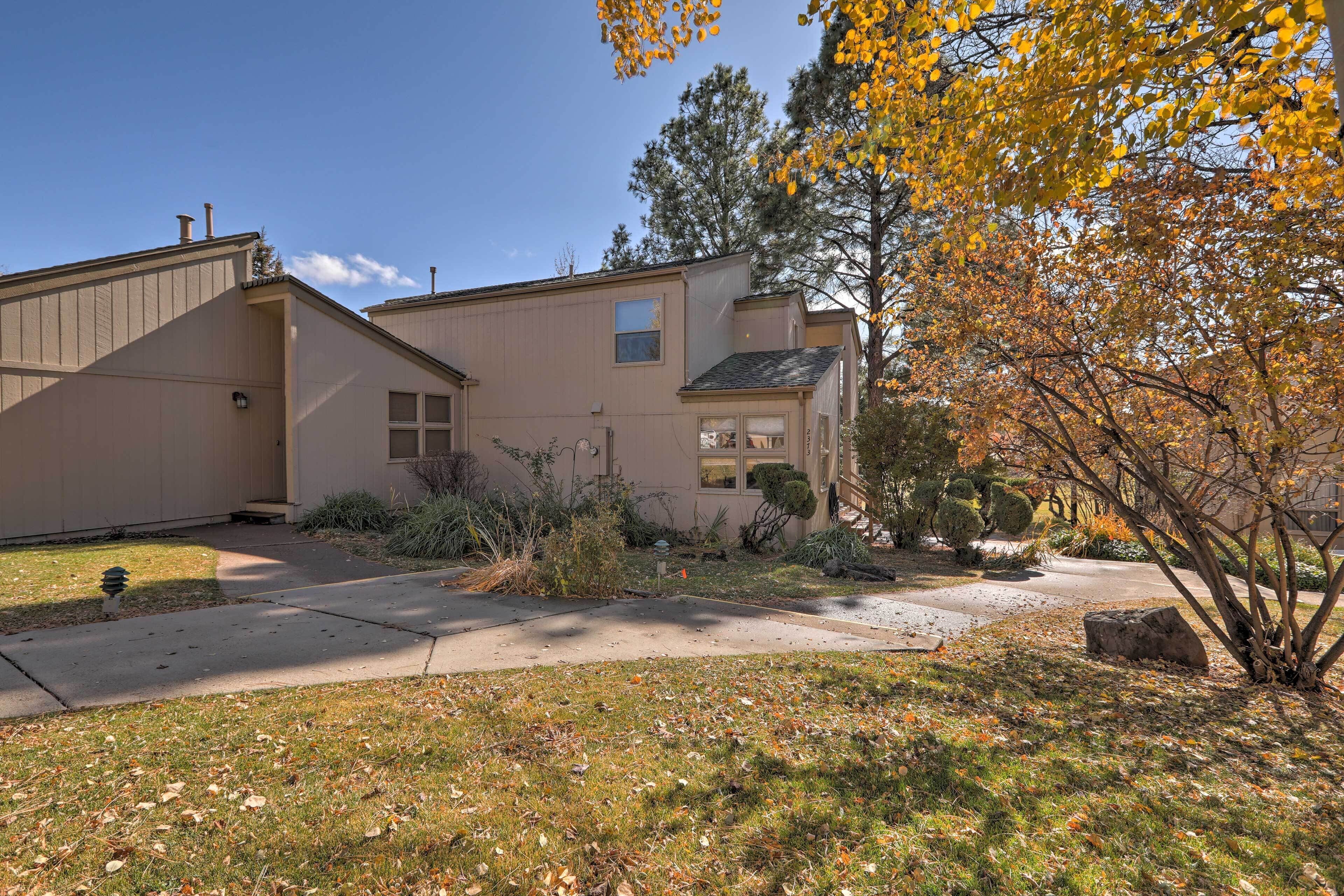 A two-story house with a front yard, a driveway, and a small garden area.